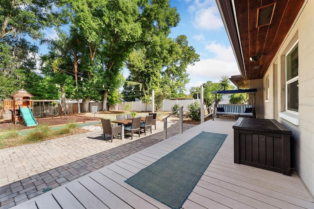 Huge park like backyard with a raised deck and paver patio.