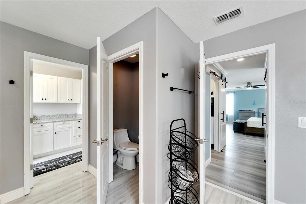 BEAUTIFUL NEUTRAL PAINT AND FLOORING CHOICES FOR THE PRIMARY BATH EN SUITE ADJACENT TO THE LAUNDRY AREA WITH ALL NEW CABINETRY AND GRANITE COUNTERTOPS