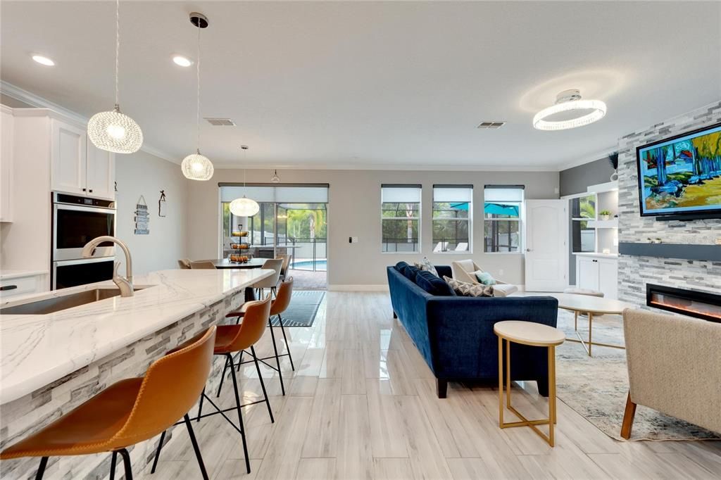 FABULOUS MODERN KITCHEN COMPLETELY REMODELED WITH HIGH GLOSS WOOD LOOK TILE THROUGHOUT THE HOME. KITCHEN ISLAND SHOWCASES BEAUTIFUL STONEWORK MATCHING THE ALL NEW ENTERTAINMENT WALL WITH ELECTRIC FIREPLACE