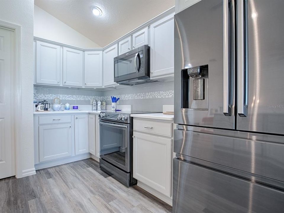 BLACK STAINLESS APPLIANCES WITH BOTTOM FREEZER REFRIGERATOR AND SMOOTH TOP ELECTRIC BUILT-IN STOVE.  ATTRACTIVE TILE BACKSPLASH.