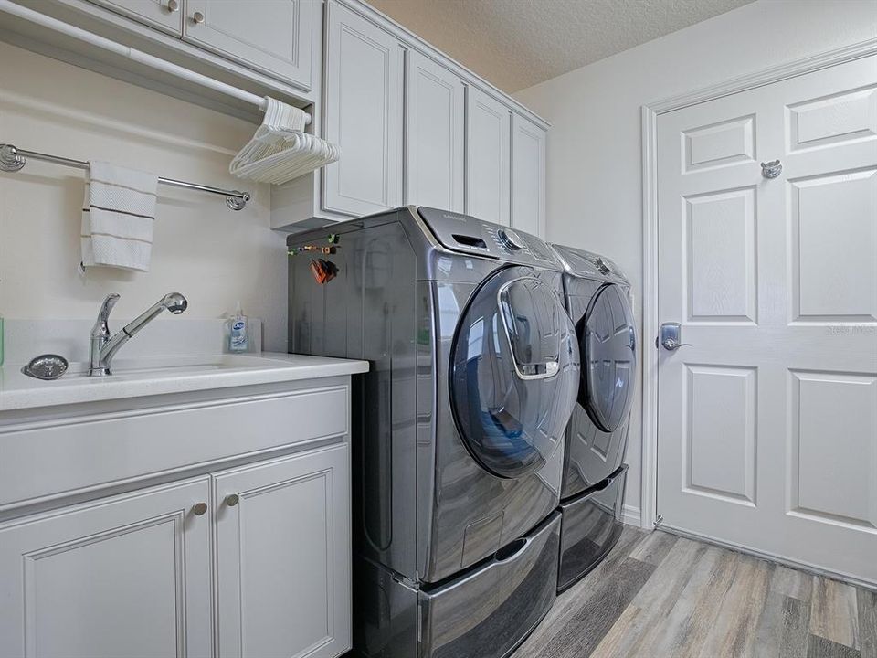 BUILT-IN SINK WITH LOTS OF EXTRA CABINET SPACE, HANGING RACK, AND FRONT LOAD WASHER AND DRYER ON PEDESTALS THAT DO CONVEY WITH THE HOME.  THIS DOOR LEADS TO THE OVERSIZED 2 CAR+ GOLF CART GARAGE.
