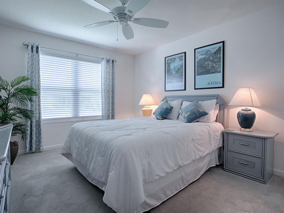FRONT GUEST BEDROOM WITH CARPET FLOORING AND CEILING FAN.