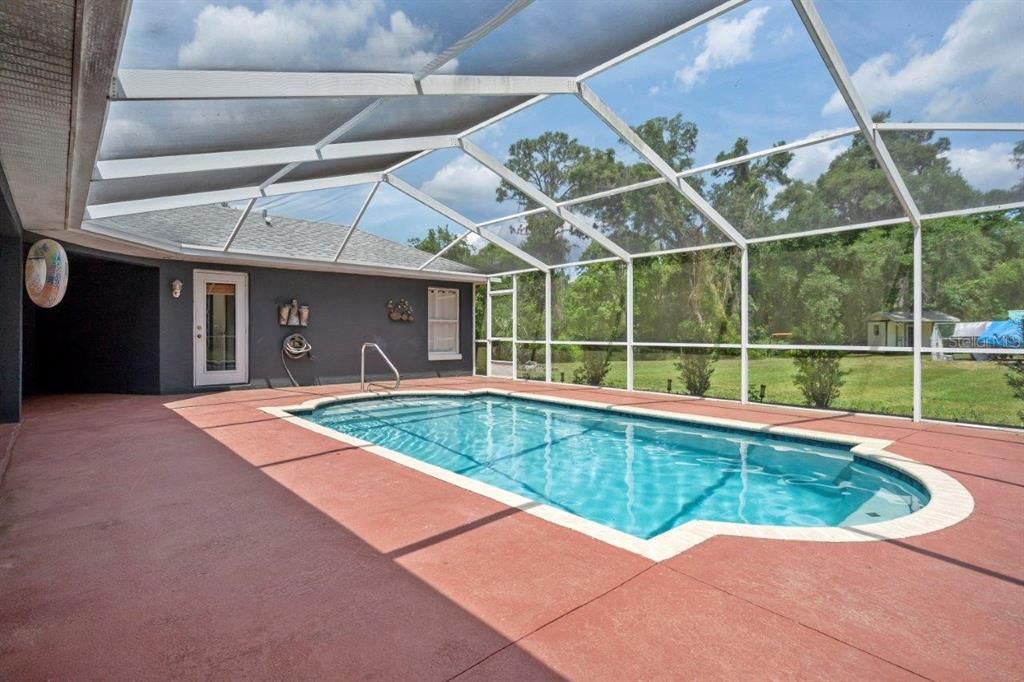 Huge 35'x27' screen enclosed lanai with a beautiful in ground pool, covered sitting area, and views of the back yard.