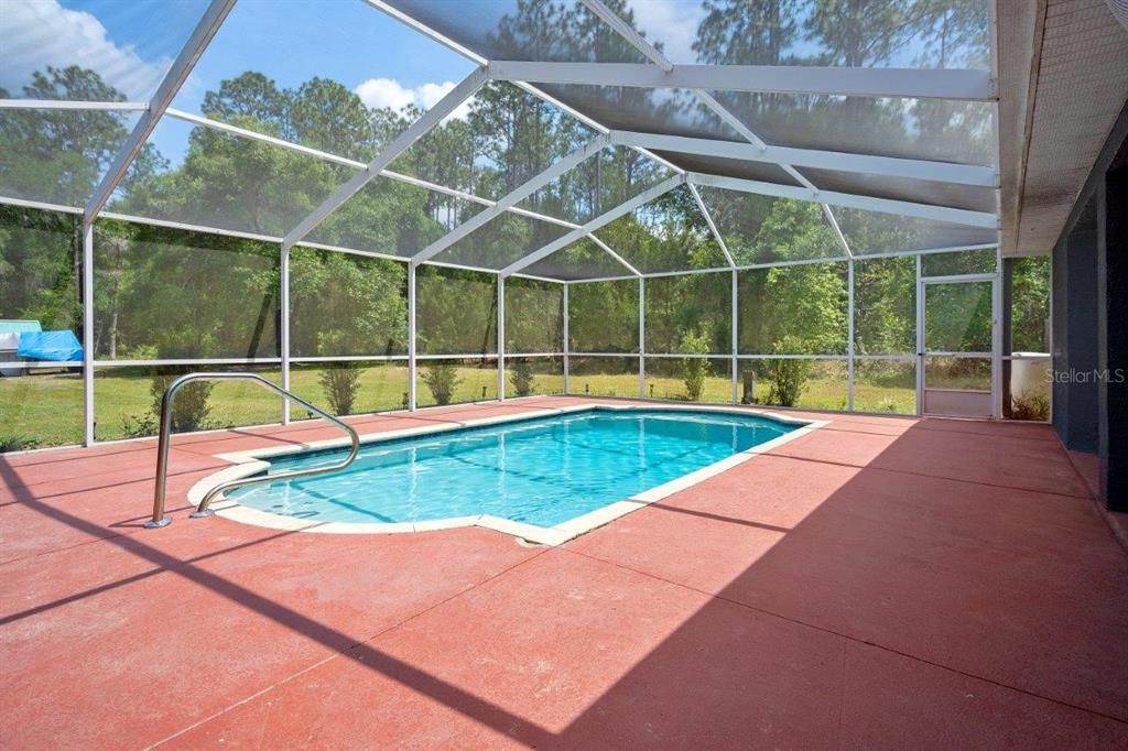 Huge 35'x27' screen enclosed lanai with a beautiful in ground pool, covered sitting area, and views of the back yard.