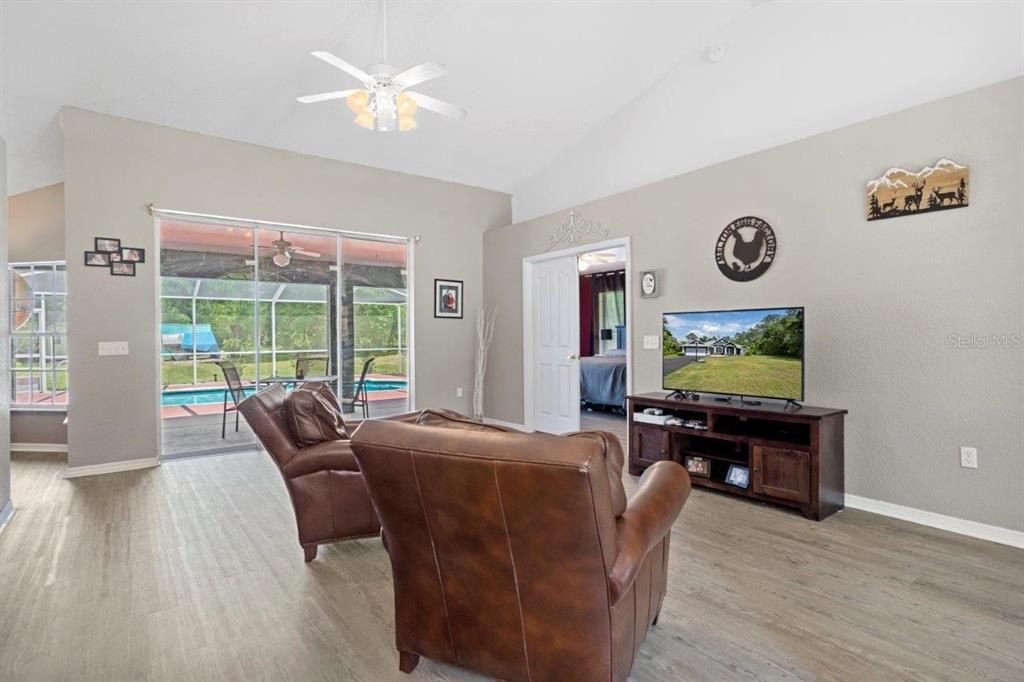 Living room located off the entryway featuring laminate plank flooring, views of the pool and back yard.