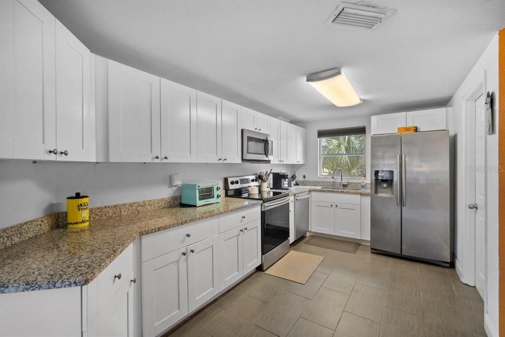 Spacious kitchen featuring stainless steel appliances, granite countertops, and shaker style cabinets.