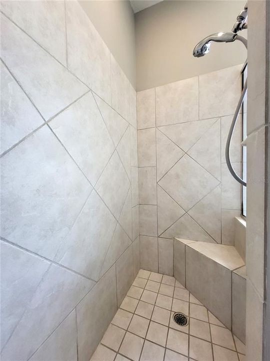 Tiled shower with built-in seat, and adjustable hand-held spray.