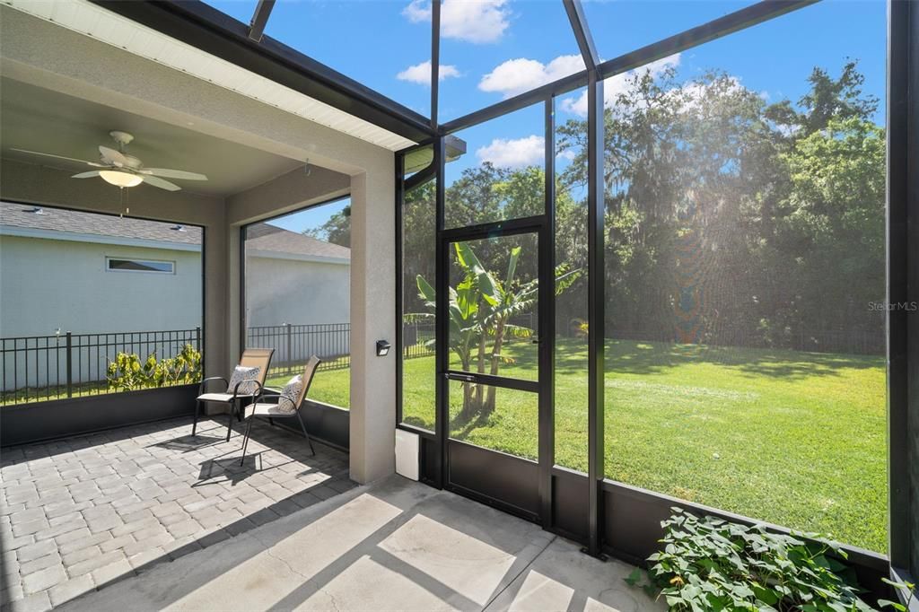Screened in lanai that has been extended for optimal space with views of the sprawling backyard that backs up to the nature preserve.