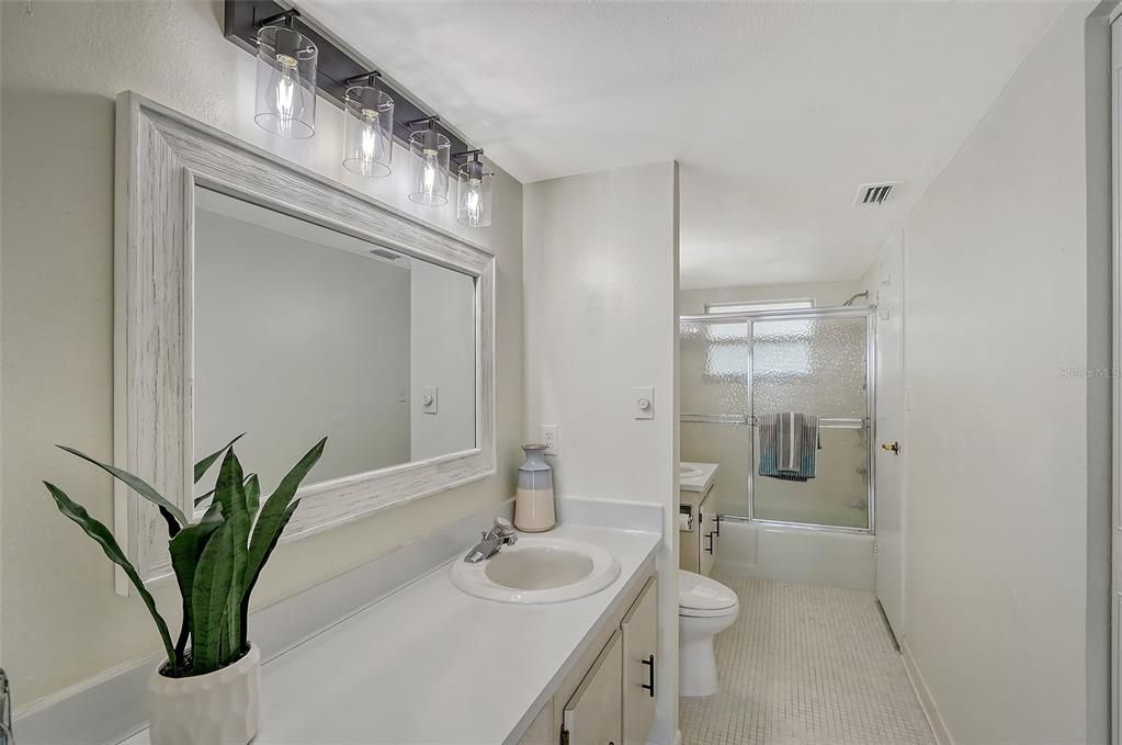 Bathroom with separate vanities and two sinks.