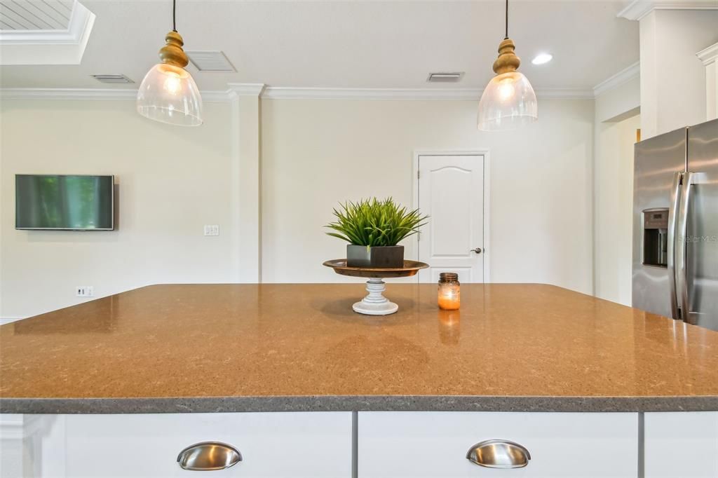 Enormous kitchen island with plenty of storage and gleaming quartz countertops. Decorator drop lights and hardware.