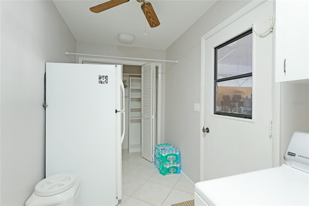 Large laundry room with utility sink, extra fridge, door to garage, cabinetry and storage closet.