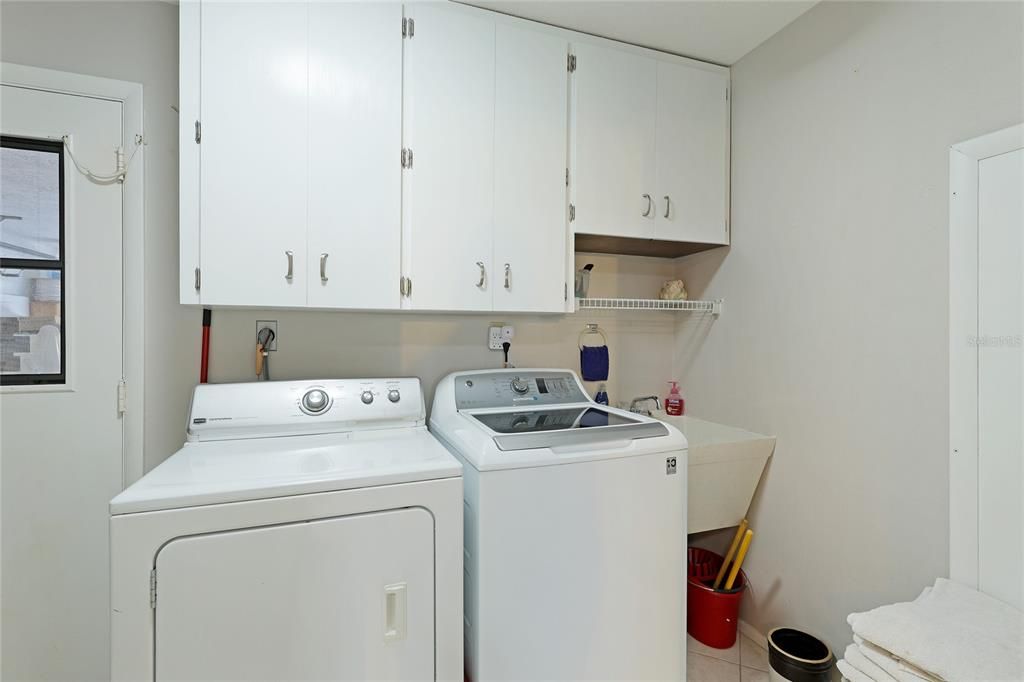 Large laundry room with utility sink, cabinetry and storage closet.