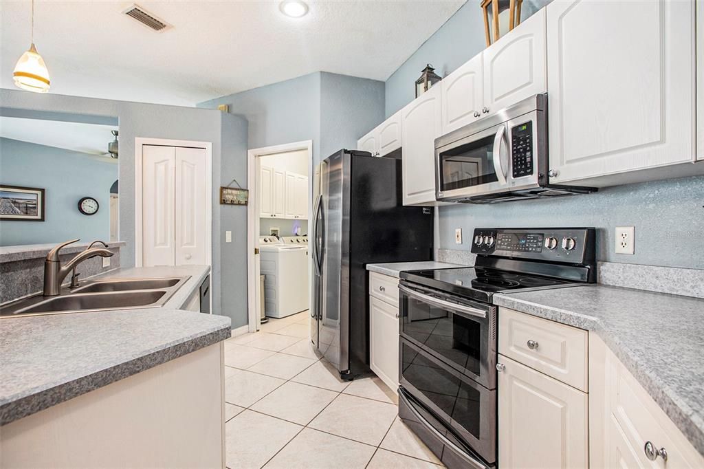 Kitchen equipped with stainless steel appliances, ample cabinets, pantry closet and a breakfast bar.