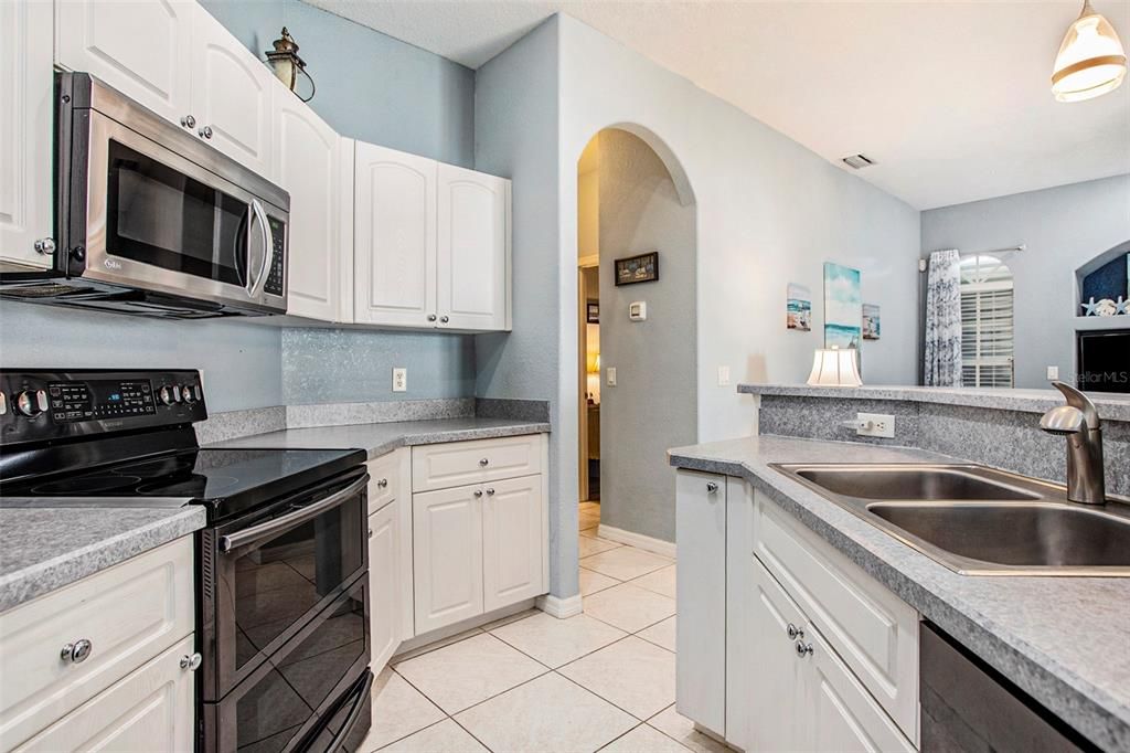 Kitchen equipped with stainless steel appliances, ample cabinets, pantry closet and a breakfast bar.