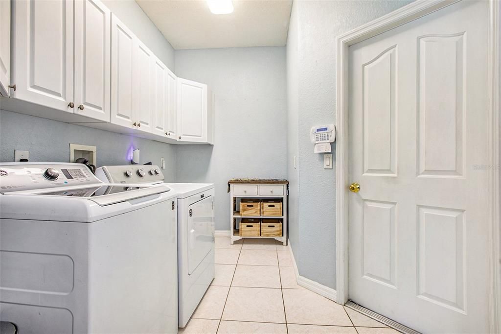 Equipped inside laundry room right off of kitchen, with cabinets, sink, pantry closet, and washer & dryer.