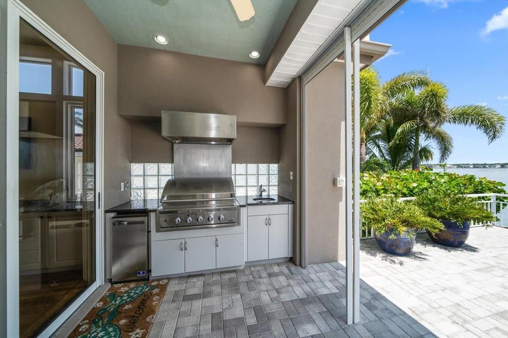 Outdoor kitchen, gas grill with commercial exhaust hood, sink and ice maker.