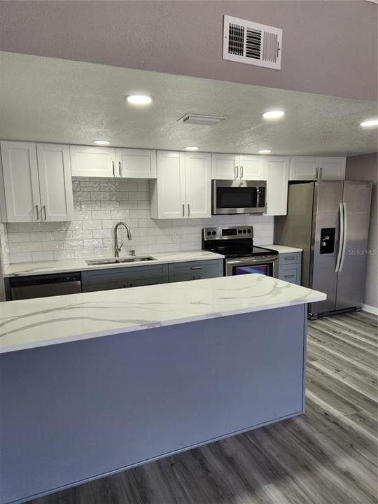 Beautiful quartz counters with grey streak ...cabinets are white on top and grey below