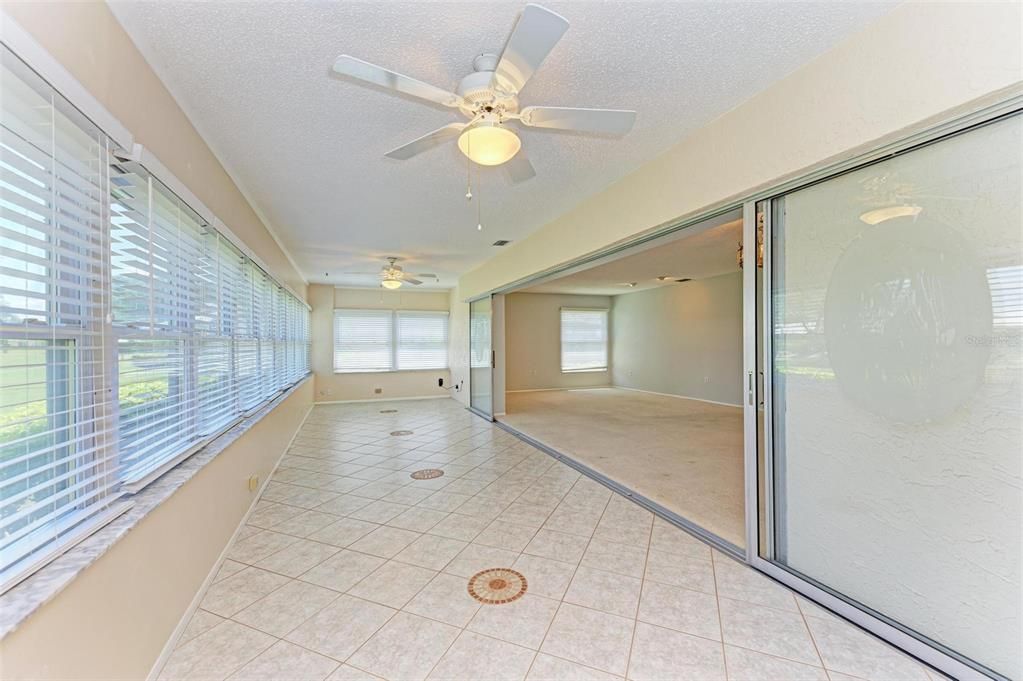 Enclosed lanai under air with sliding glass doors that pocket away looking into living room.