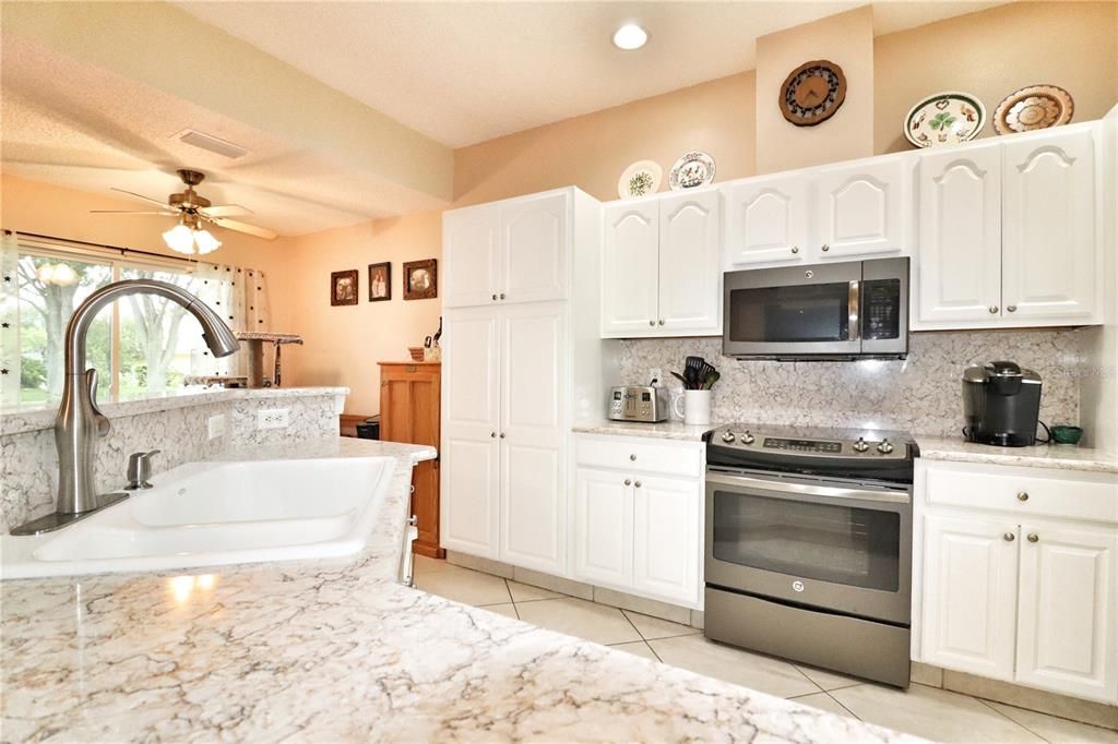 The spacious kitchen boasts sturdy solid wood cabinets, quartz counter tops
