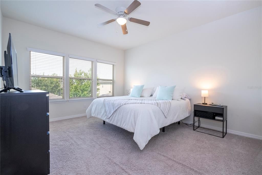Upstairs Master Bedroom with huge windows bringing natural light and ceiling fan.