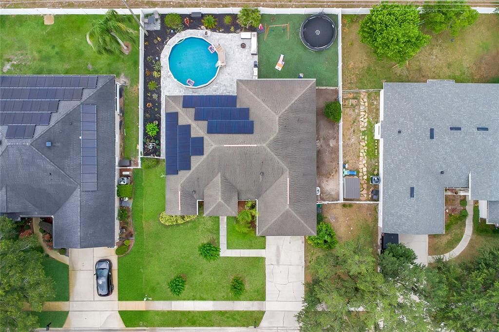 Aerial view of home with paid-off solar system, fully fenced yard, and pool