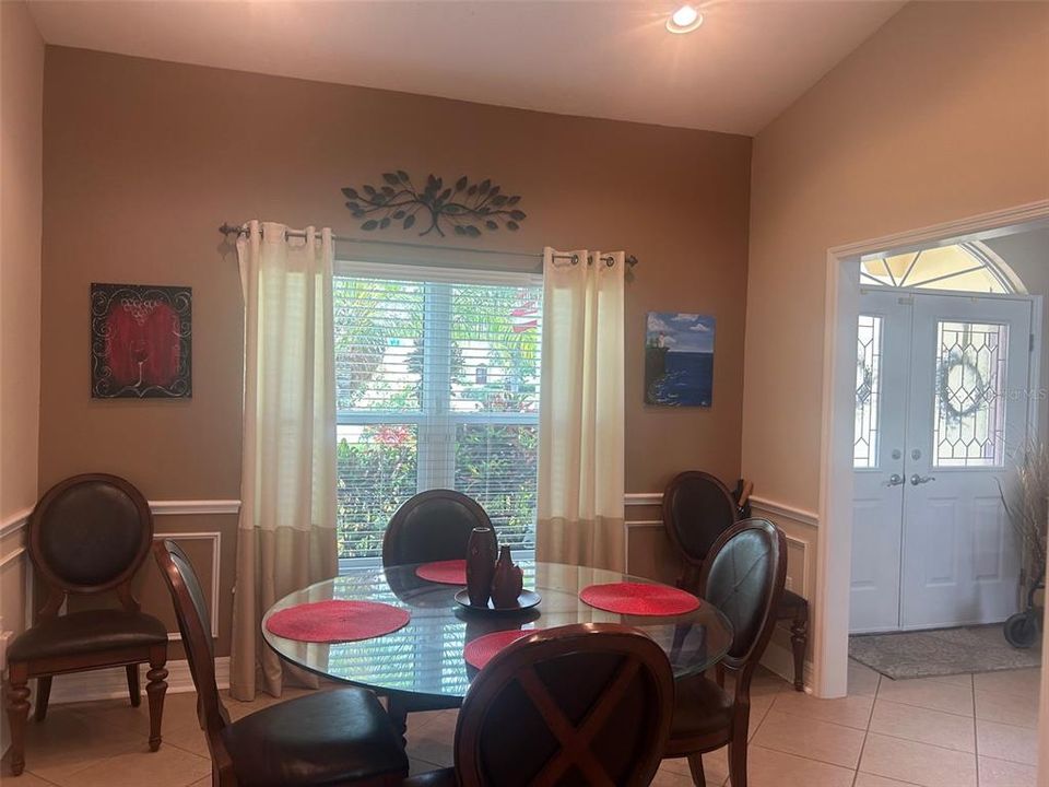 Dining room with garden view has vaulted ceiling, recessed lighting and chair rail wainscotting
