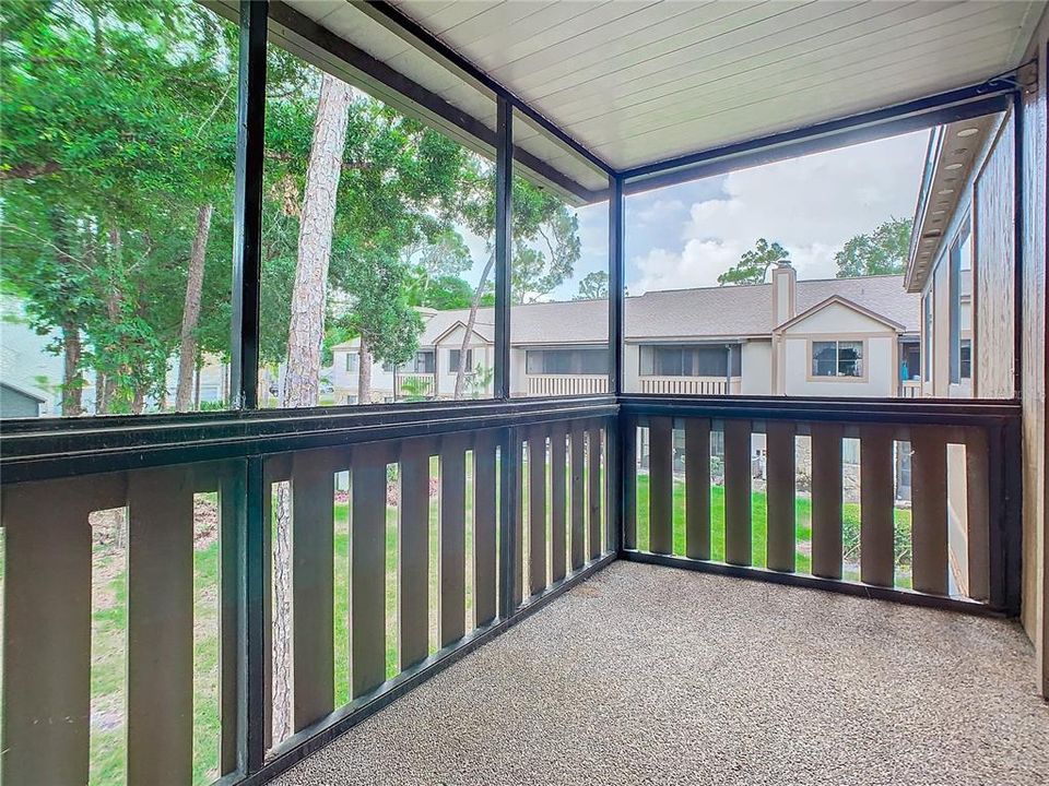 Screened-in balcony overlooks wooded area.