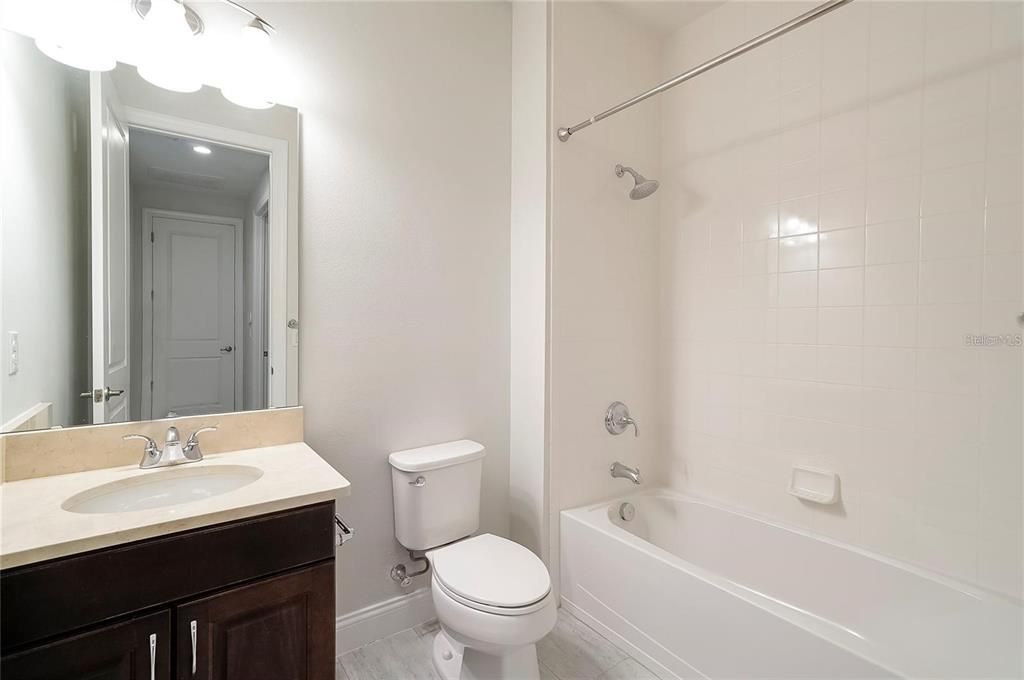 full sized bathroom with granite vanity area, sink, tub and shower