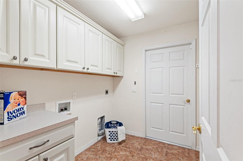 LAUNDRY ROOM WITH PLENTY OF CABINETRY. DOOR LEADS TO GARAGE