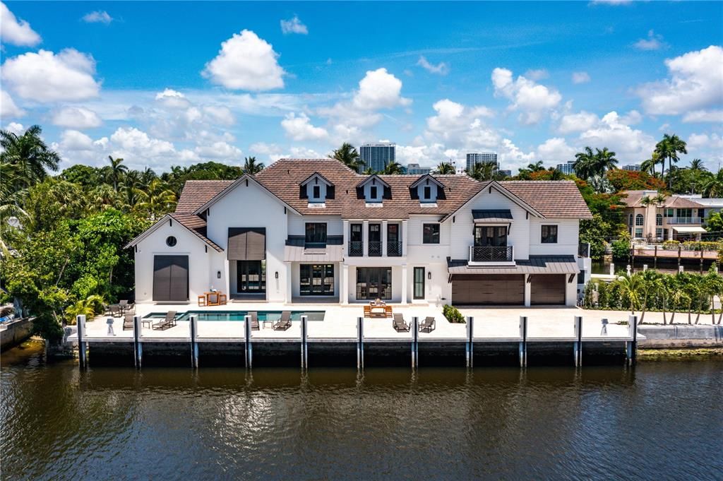 Expansive backyard, reminiscent of a peninsula retreat, offers a serene setting with panoramic water views, complemented by a water view loggia flowing seamlessly to the patio and sparkling pool with a sun-shelf and Jacuzzi.