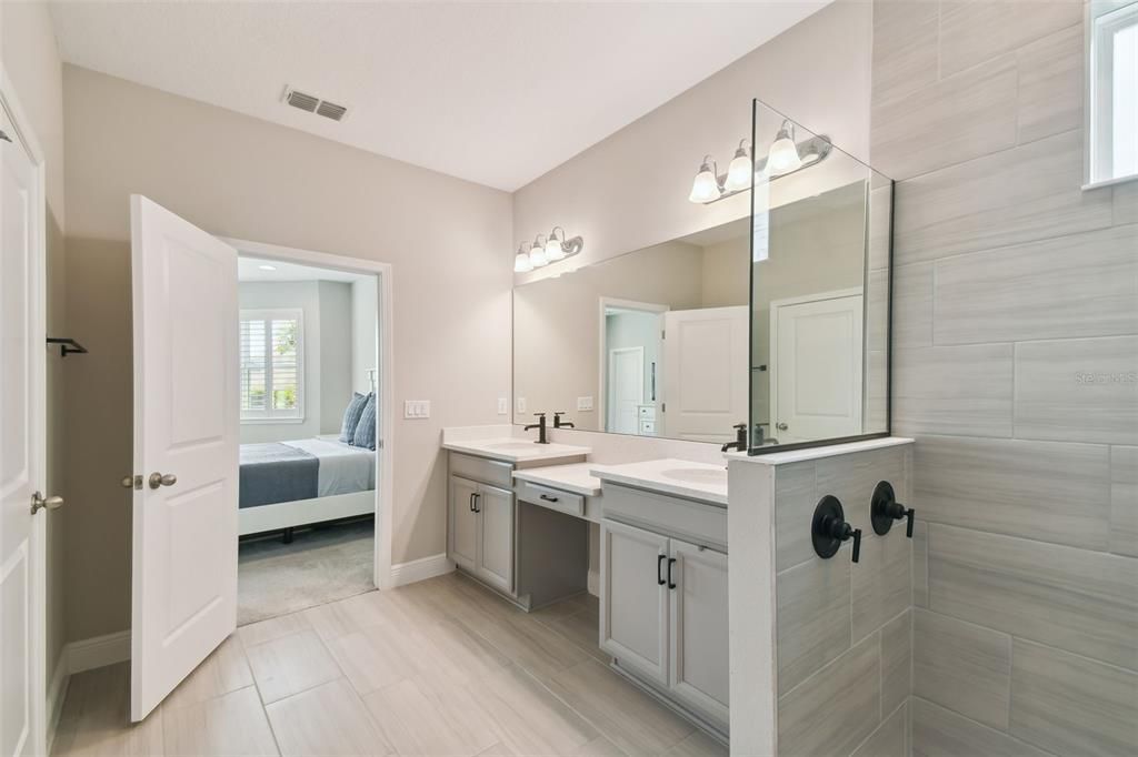 Beautiful owner’s bathroom featuring double vanities, a walk-in shower, and two walk-in closets, one with a custom closet system.