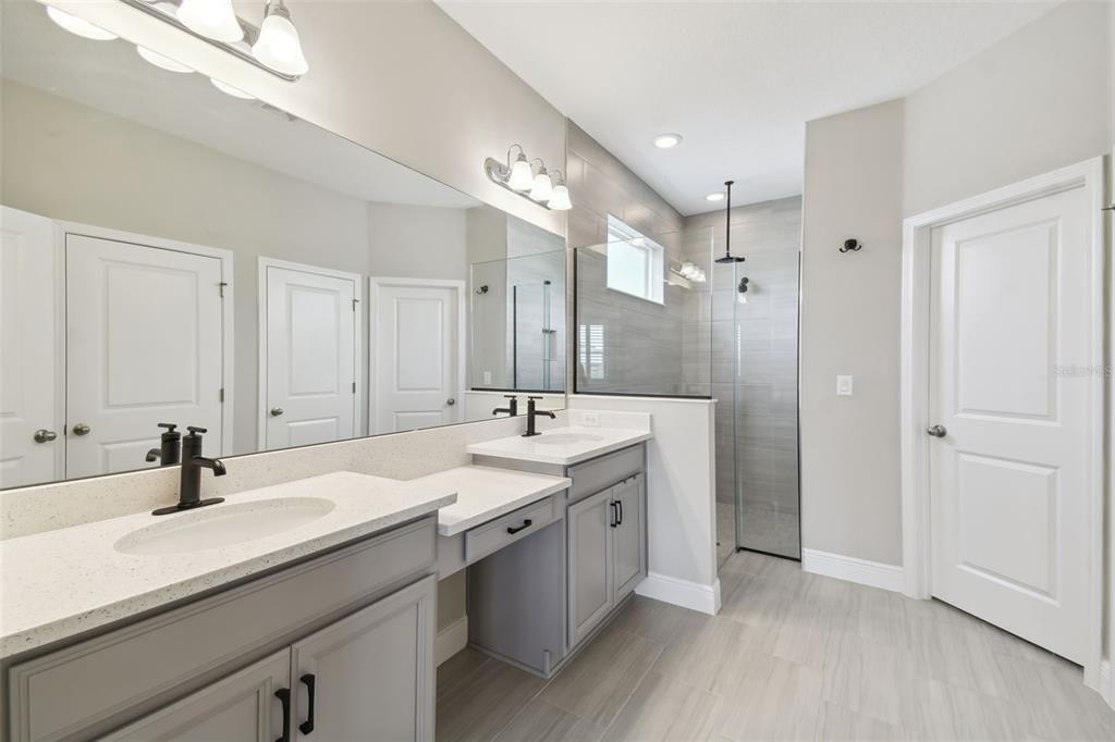 Beautiful owner’s bathroom featuring double vanities, a walk-in shower, and two walk-in closets, one with a custom closet system.