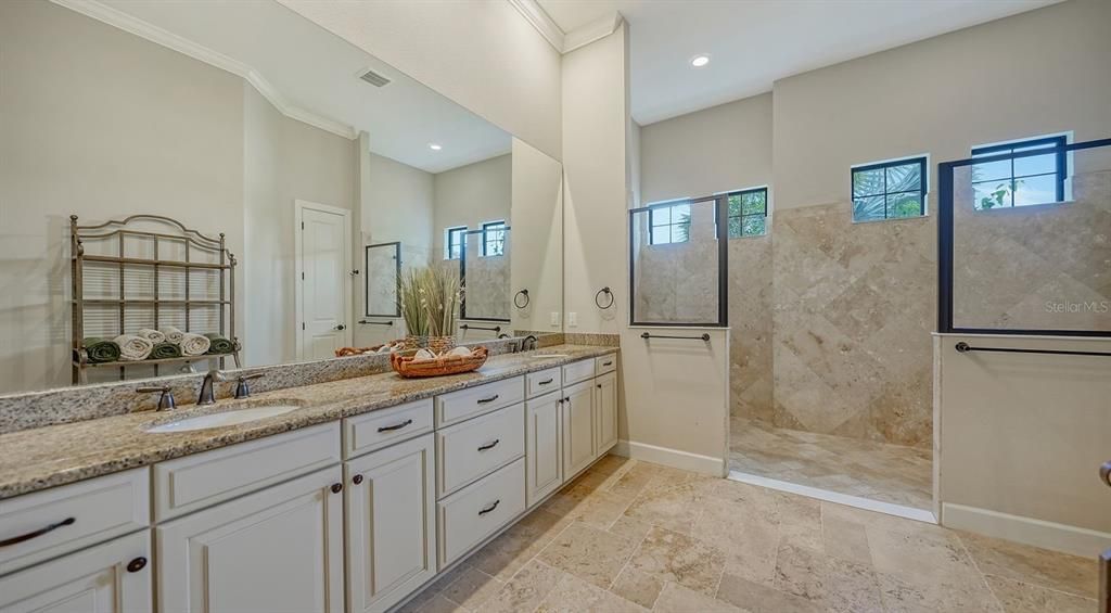 Spacious primary ensuite bathroom with wall of cabinets, dual sinks and dual shower