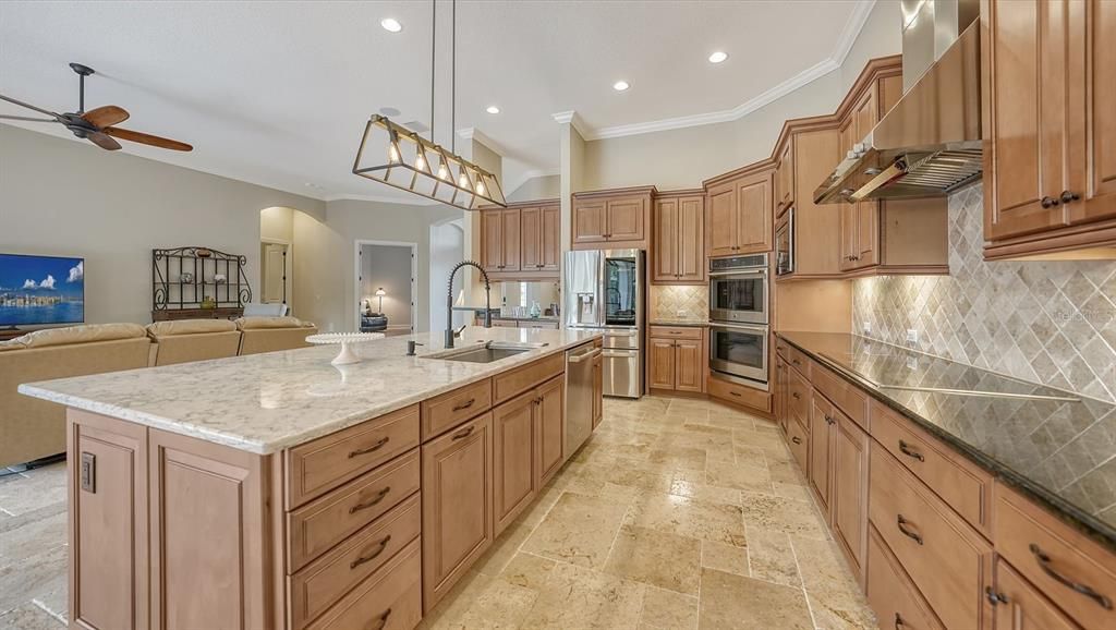 Island countertop is quartz - side cabinetry is enhanced with travertine backsplash and granite countertops.Designer kitchen sink with accompanying enhancements.