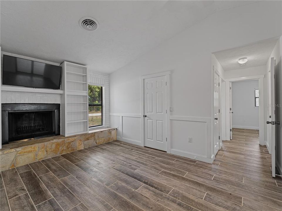 Family room with cathedral ceiling, raised wood burning fireplace and build-in shelves.