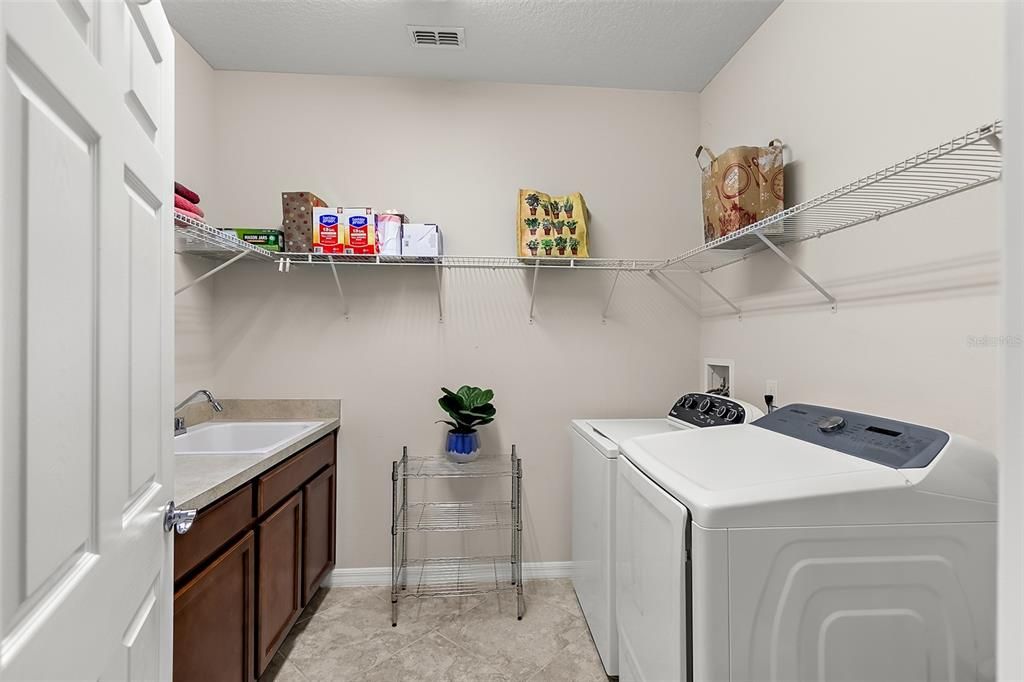 1st floor laundry with built-in utility sink and cabinet storage
