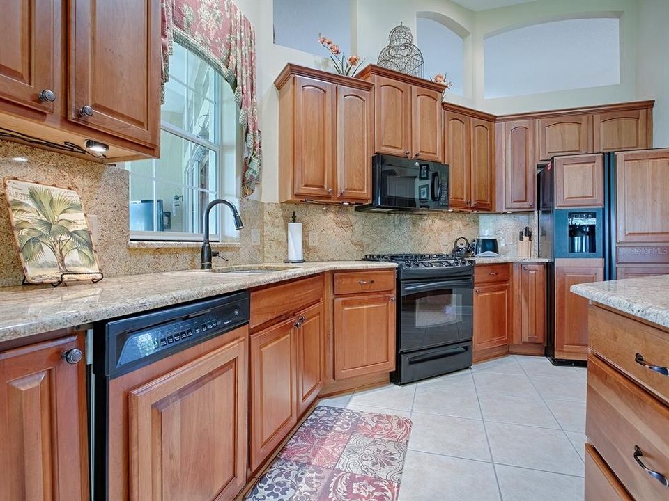 CABINETRY TRIM ON DISHWASHER AND REFRIGERATOR, BLACK APPLIANCES WITH BUILT-IN GAS STOVE.