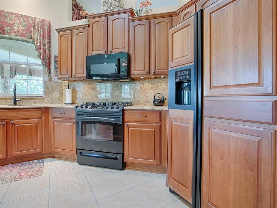 LOVELY CHERRY CABINETRY WITH TOP CROWN TRIM, GRANITE COUNTER TOPS AND BACKSPLASH! A PASS-THRU WINDOW OUT TO THE ENCLOSED LANAI.