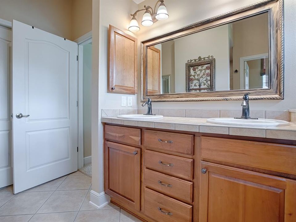 BATH WITH TILED COUNTER TOPS, DUAL SINKS, CUSTOM MIRROR. BEHIND THE DOOR IS A POCKET DOOR WITH LARGE WALK-IN CLOSET.