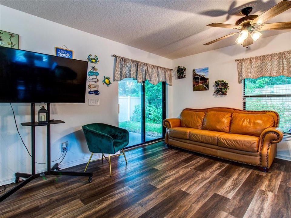 Open Concept Main Living Area With Luxury Vinyl Floors ; Patio Door Leads to Back Patio & Backyard