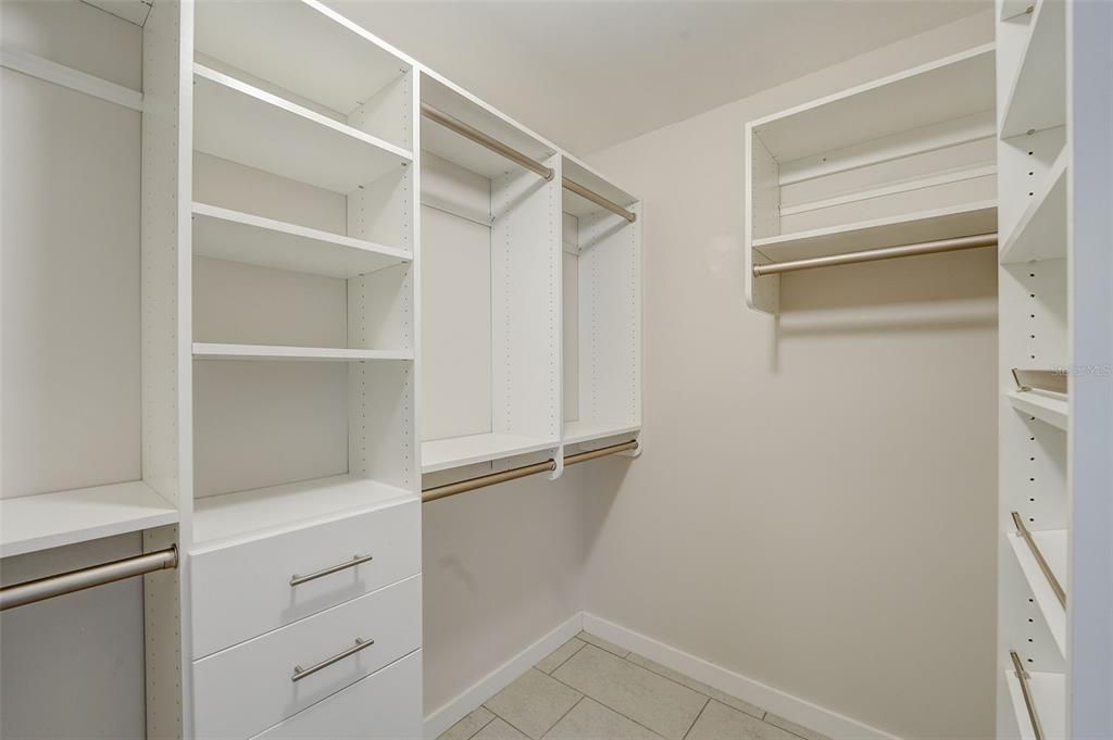 Primary bedroom walk-in closet with custom shelving