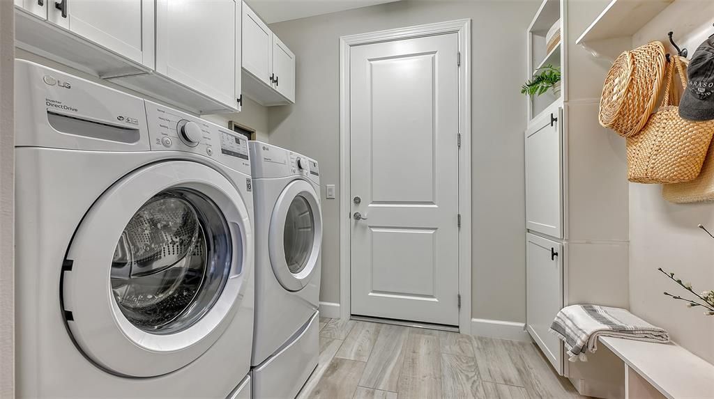 Indoor laundry room has a utility sink and many built-in cabinets...