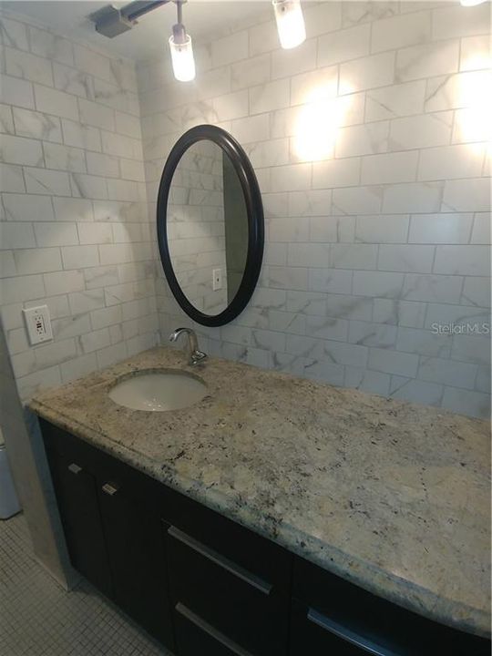 Lovely renovated bath. Grey subway tiles, granite vanity with lots of storage space and updated lighting.