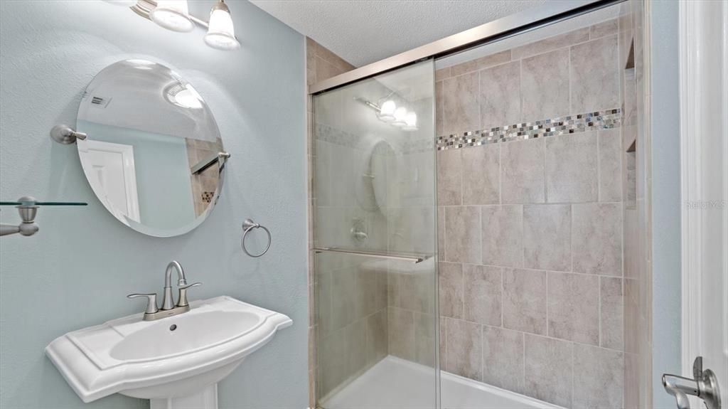 Additional bathroom area within master bath with door, pedestal sink, toilet room, and shower