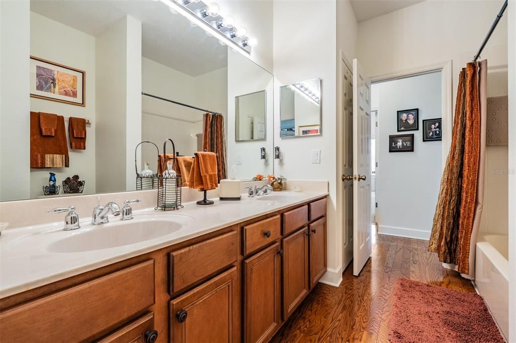 Guest/hall bathroom with dual sinks, wood cabinets, tub/shower combo and linen closet