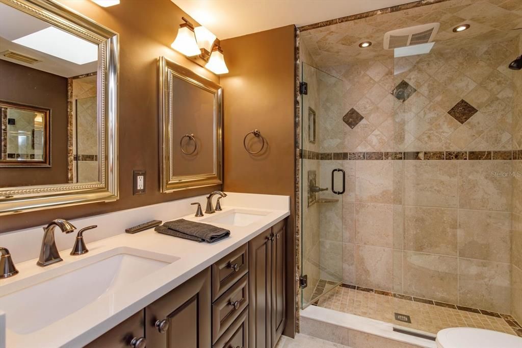 Upstairs Bathroom that has been completely renovated.  Walk in shower with glass enclosure, double vanity, new designer lighting, double medicine cabinet behind the mirrors, and a mounted TV to enjoy during your morning routine!