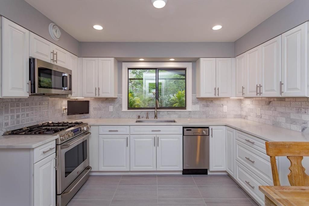 Brand new kitchen with gas range, stainless appliances, tumbled marble backsplash and lots of storage.  The view is of the covered / screened in expansive patio that overlooks the amazing backyard.  A gardener's paradise!