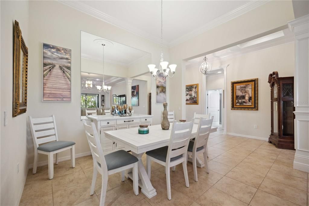 Formal dining area with upgraded light fixtures and crown molding on high ceilings creating spacious feeling.