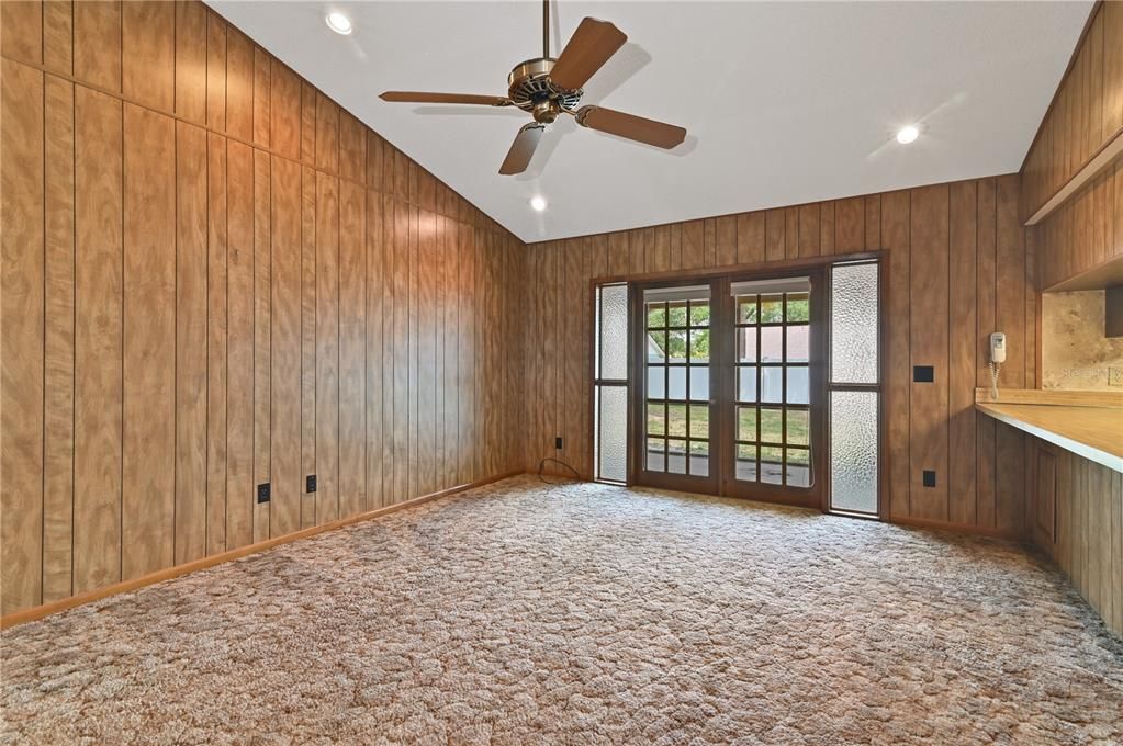 The vaulted ceilings, recessed lighting, and French doors can be the start of something creative for this family room separated from the kitchen with a breakfast bar.