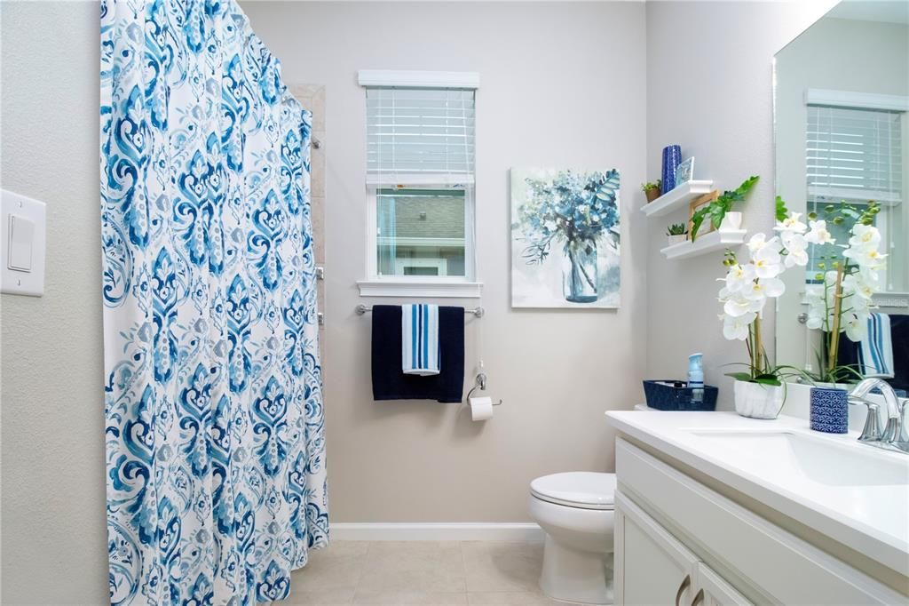 Bathroom two with quartz counters and bathtub is bright and light with linen closet